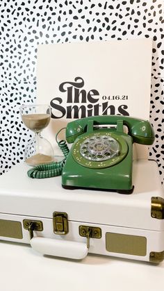 an old fashioned green phone sitting on top of a white suitcase next to a sign that says the smiths