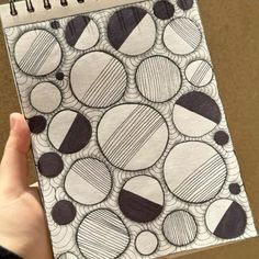 a hand holding a notebook with black and white circles on it