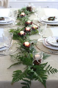 the table is set with candles and greenery