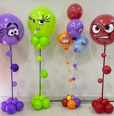 several balloons with faces on them are lined up against a wall, one has eyes and the other has nose