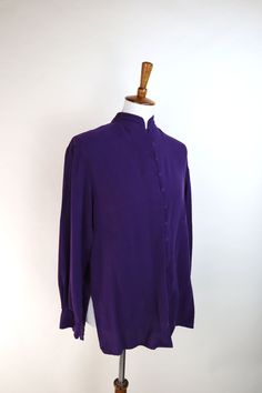 A posh and sophisticated top to be sure. This 90's silk Chinese style blouse in a dark moody eggplant purple is top notch quality. The shirt features a soft silk weave, stand collar, loop buttons and deep side splits going up to the waist. It has a lovely tunic style cut, and would look stunnin' with some wide leg linen pants. GARMENT MEASUREMENTS (in Inches) Bust: 42" Waist: 40" Hemline: 40" Shoulder Width: 17" Sleeve Length: 29" Length: 28" Estimated Best Fit: Size Small **all Measurements are Fall Solid Silk Tops, Long Sleeve Silk Top In Solid Color, Long Sleeve Silk Tops In Solid Color, Purple Fitted Button-up Blouse, Purple Button-up Blouse For Daywear, Fitted Long Sleeve Purple Blouse, Long Sleeve Purple Silk Tops, Classic Purple Formal Tops, Long Sleeve Purple Blouse For Daywear