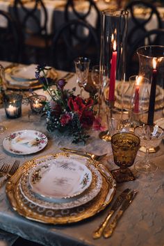 the table is set with plates, silverware and candles