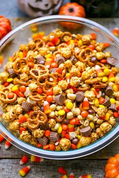 a bowl filled with candy corn and pretzels