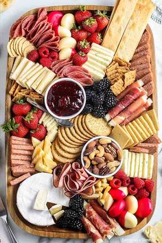 a platter filled with cheese, crackers, strawberries, and other snacks