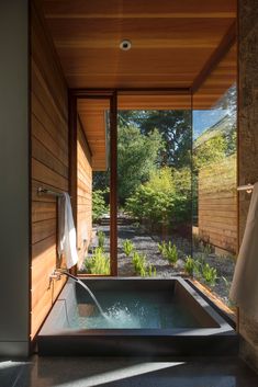 an outdoor jacuzzi tub in the middle of a room with wooden walls and windows