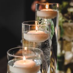 three candles are sitting in glass vases on a table