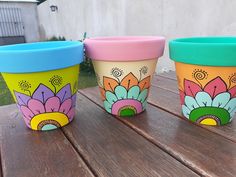 three colorful cups sitting on top of a wooden table