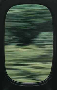 an airplane's window is shown with blurry trees in the background