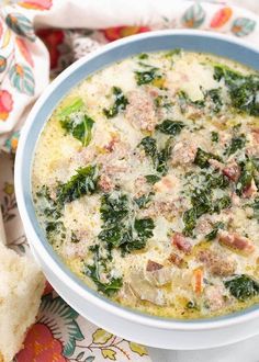 a bowl of soup with meat, spinach and cheese in it on a floral table cloth