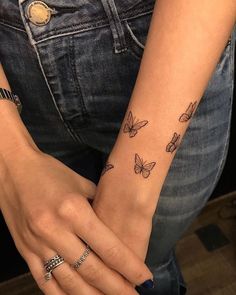 a woman's arm with butterfly tattoos on her left wrist and the other hand