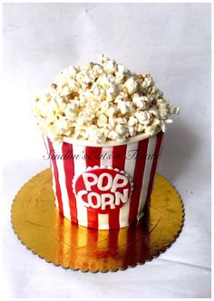 a red and white striped popcorn cup sitting on top of a gold plate