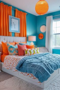 a bedroom with blue walls, orange curtains and a white bed in the center is decorated with bright colored pillows