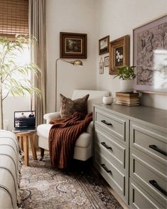 a living room with a couch, dresser and pictures on the wall above it's headboard