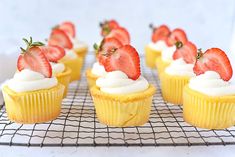 small cupcakes with strawberries on top sitting on a cooling rack