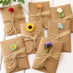 six brown envelopes tied with twine and decorated with colorful flowers on each side