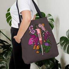 a woman carrying a tote bag with flowers and a knife on the inside, in front of a potted plant