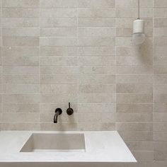 a white sink sitting under a faucet next to a wall mounted soap dispenser