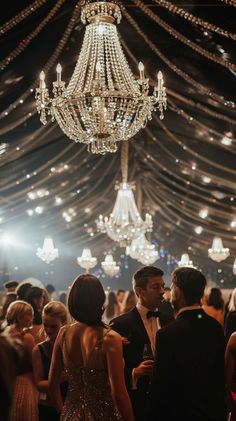 a group of people standing under a chandelier in a room filled with lights