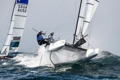 two sailboats racing in the ocean on choppy water with one boat upside down