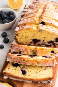 sliced loaf of lemon blueberry bread on a cutting board next to fresh blueberries