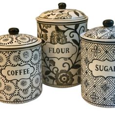 three canisters with black and white designs on the sides, one has a flower design