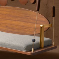 a wooden bed frame with a blue cushion and two brass hooks hanging from it's sides