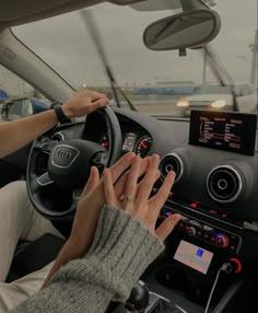 a woman driving a car with her hands on the steering wheel and an electronic screen