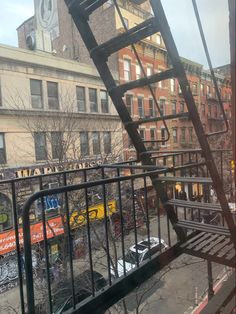 a metal staircase going up the side of a building next to a street with cars parked on it