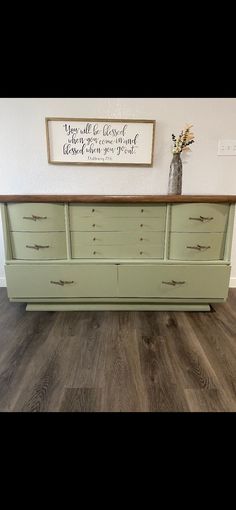 an old dresser is painted green and has some flowers in it on top of it