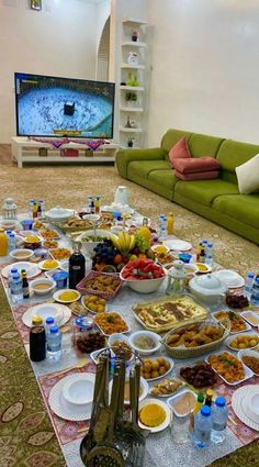 a table full of food and drinks on the floor in front of a flat screen tv