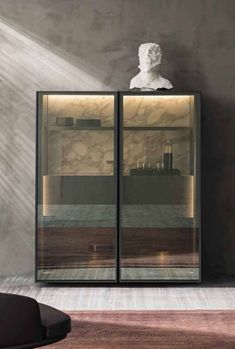 a glass cabinet with a bust on top in a room that has marble walls and flooring