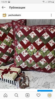 two decorative pillows on top of a bed next to a box with a gift wrapped in ribbon