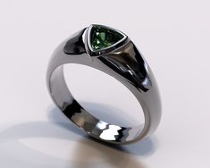 a close up of a ring with a green diamond in it on a white surface