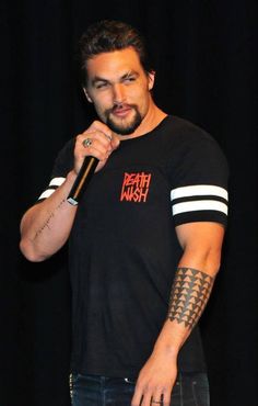 a man with tattoos on his arm holding a microphone