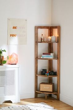 a wooden shelf with books and candles on it next to a white cabinet in a room