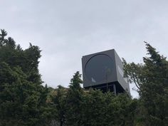 a large black object sitting on top of a lush green forest next to tall trees