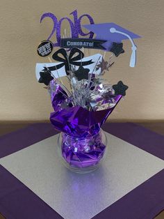 a glass vase filled with purple and black confetti on top of a table