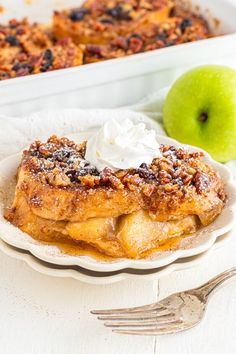 a slice of apple pie on a plate with whipped cream and an apple in the background