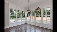 an empty room with three chandeliers hanging from the ceiling and wood flooring