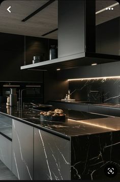 a kitchen with marble counter tops and black cabinets