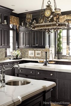 a large kitchen with black cabinets and white counter tops, an island in the middle