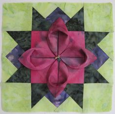 a quilted square with a pink flower on it's center and green background