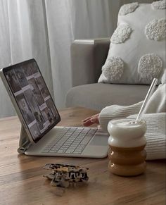 a laptop computer sitting on top of a wooden table next to a cup and saucer