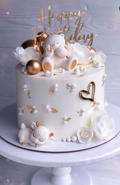 a white cake with gold decorations and teddy bears on top