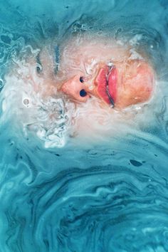 a woman is floating in the water with her head above the water's surface