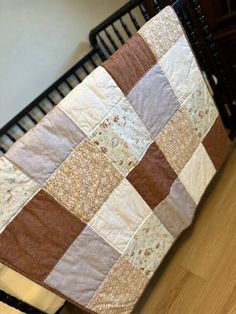 a baby crib with a brown and white quilt on it's back end