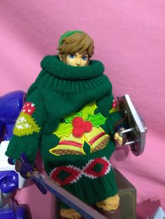 a toy figurine wearing a green sweater and holding a pair of skis