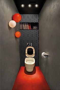 a toilet in a narrow room with black and white wallpaper on the walls behind it