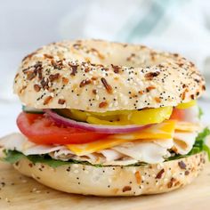 a bagel sandwich with cheese, tomato, lettuce and other toppings