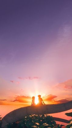 two people sitting on a surfboard at sunset